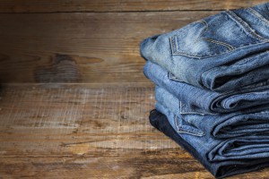 5 jeans pliés sur une table en bois