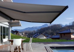 bord de piscine d'un particulier avec un grand store avec dessous des chaise et une table