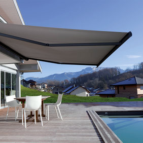 bord de piscine d'un particulier avec un grand store avec dessous des chaise et une table