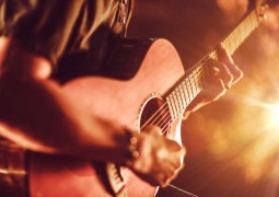 guitare acoustique tenus par un homme en jouant avec une lumière vive sur la droite