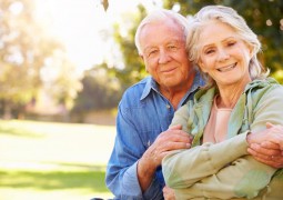 un couple de retraitée se tenant dans les bras le regard tourné vers l'objectif.