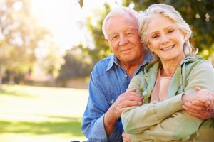 un couple de retraitée se tenant dans les bras le regard tourné vers l'objectif.